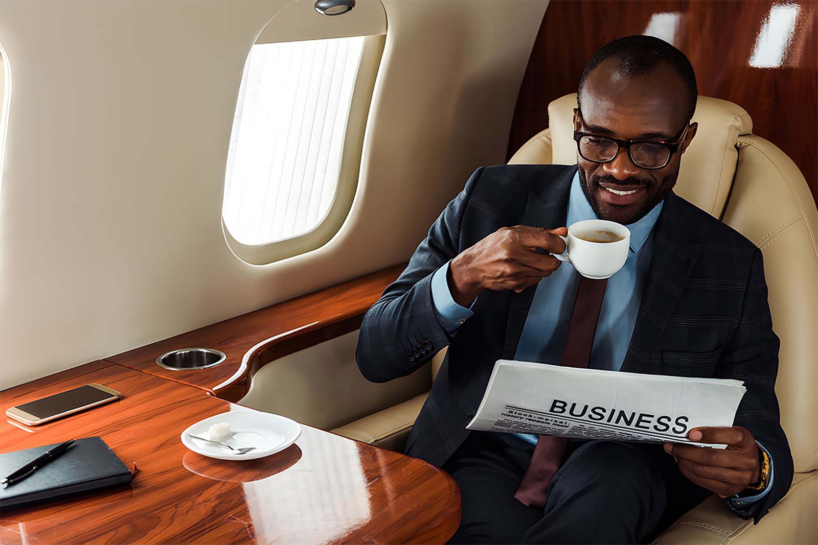 Businessman reading the newspaper and drinking coffee on a corporate charter flight.